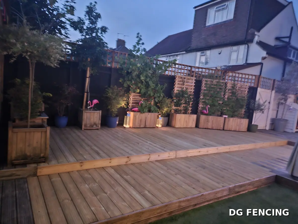 New timber decking at dusk with planters, screens and garden lighting