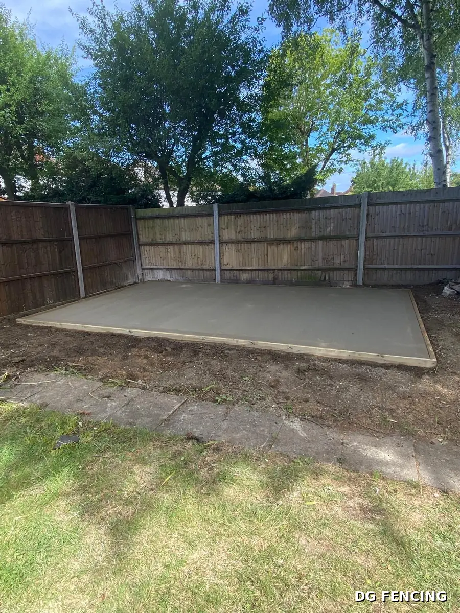Freshly laid level concrete base for a garden building, edged with timber formwork